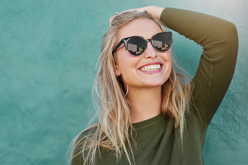 young woman smiling against teal wall